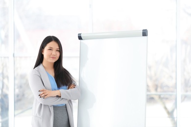 Photo of Business trainer standing near flip chart board indoors