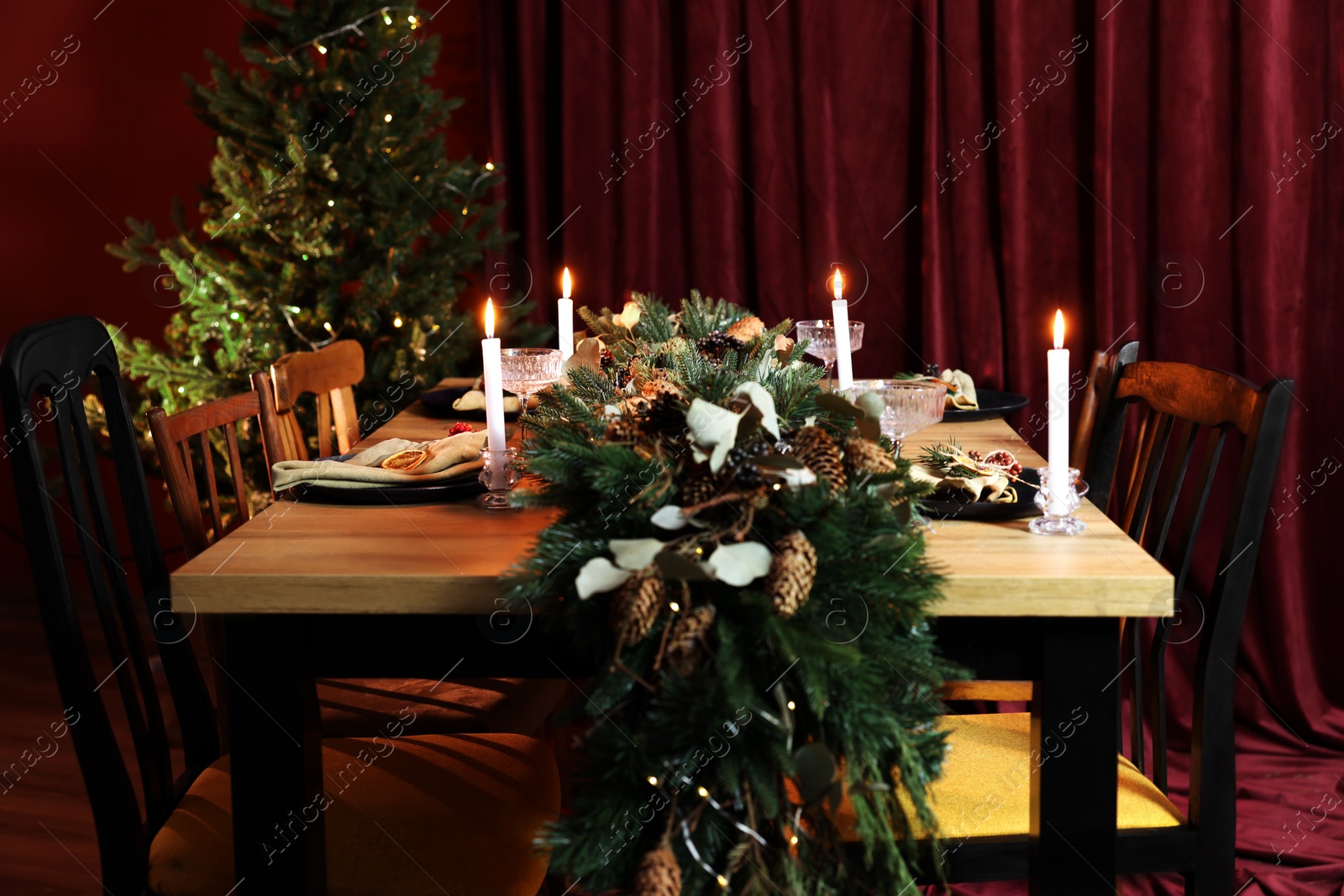 Photo of Dining table with burning candles and Christmas decor in stylish room. Interior design