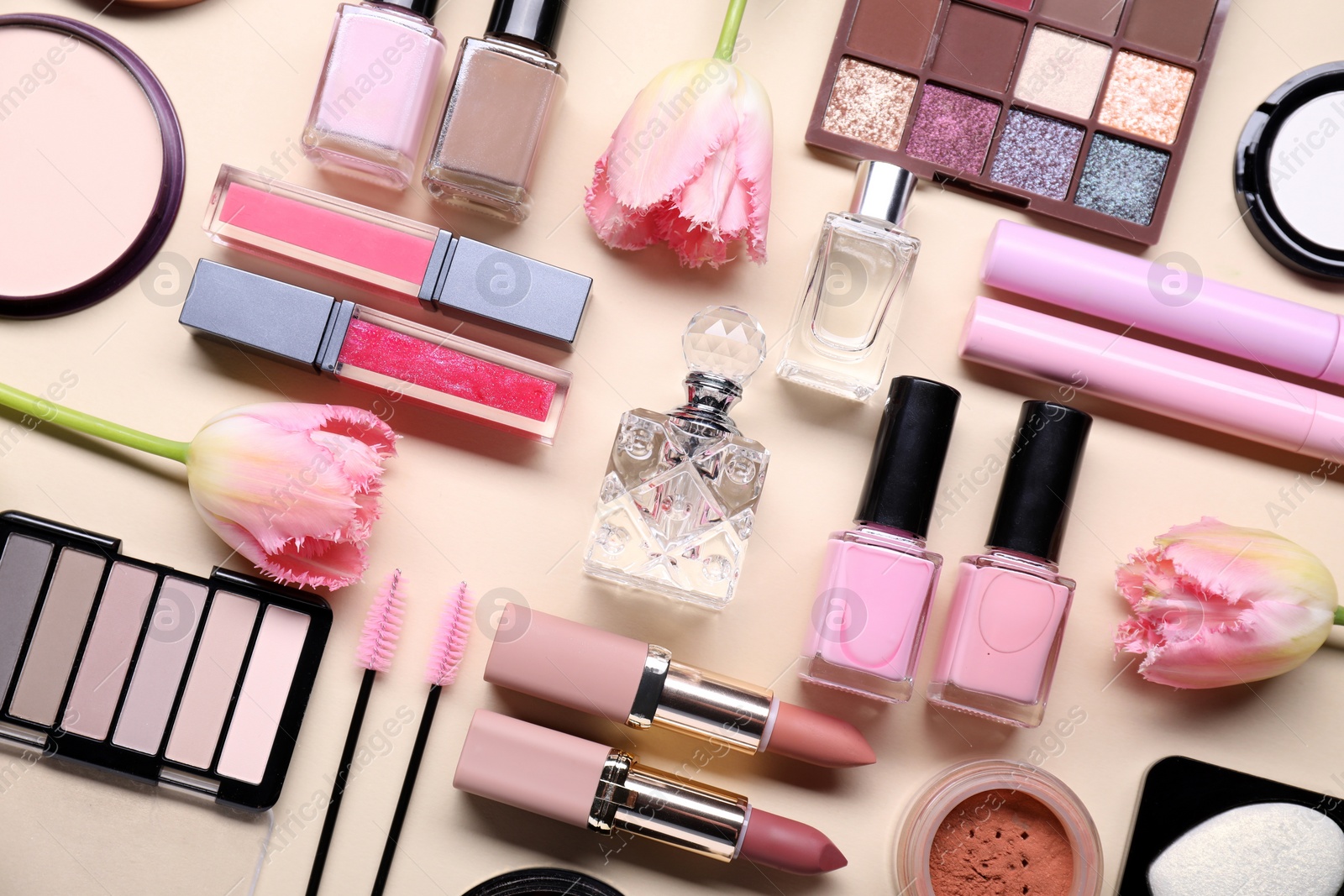 Photo of Flat lay composition with different makeup products and beautiful spring flowers on beige background