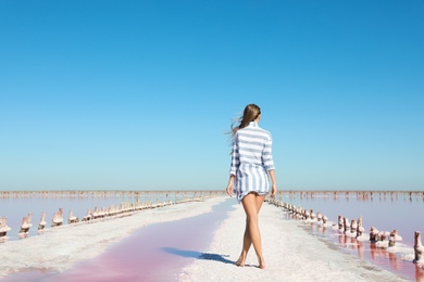 Beautiful woman posing near pink lake on summer day