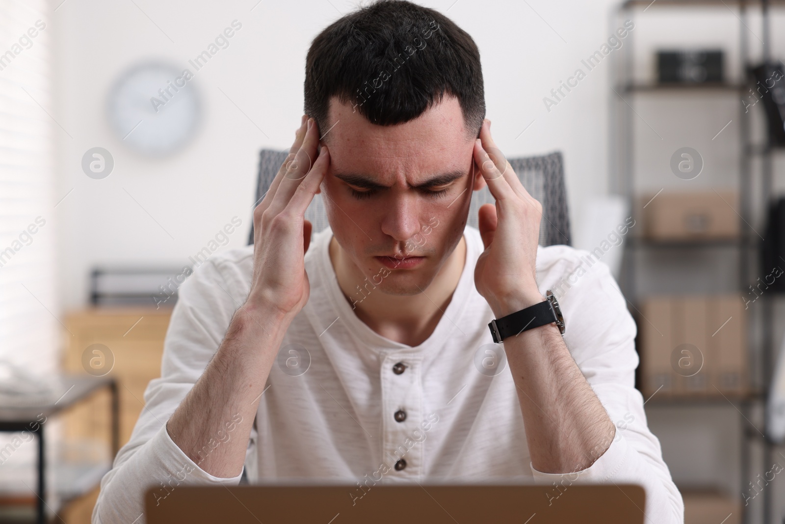 Photo of Young man suffering from headache in office