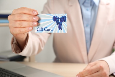 Photo of Woman with gift card at table indoors, closeup