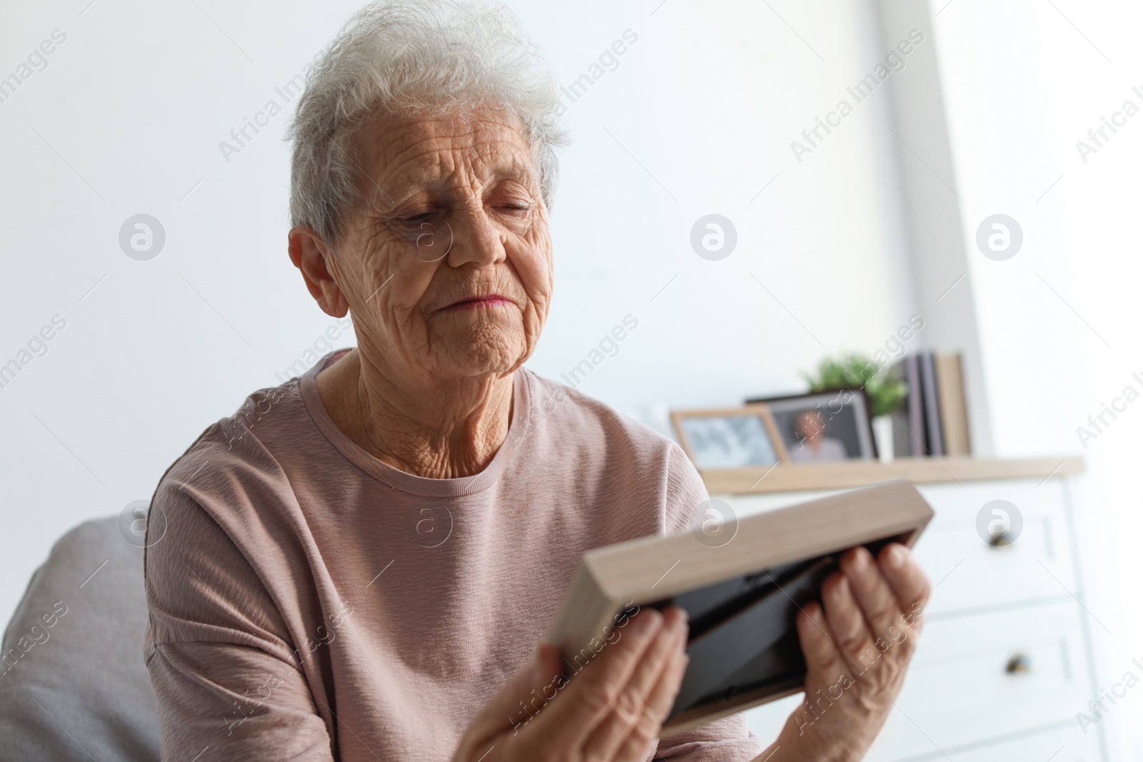 Photo of Elderly woman with framed photo at home