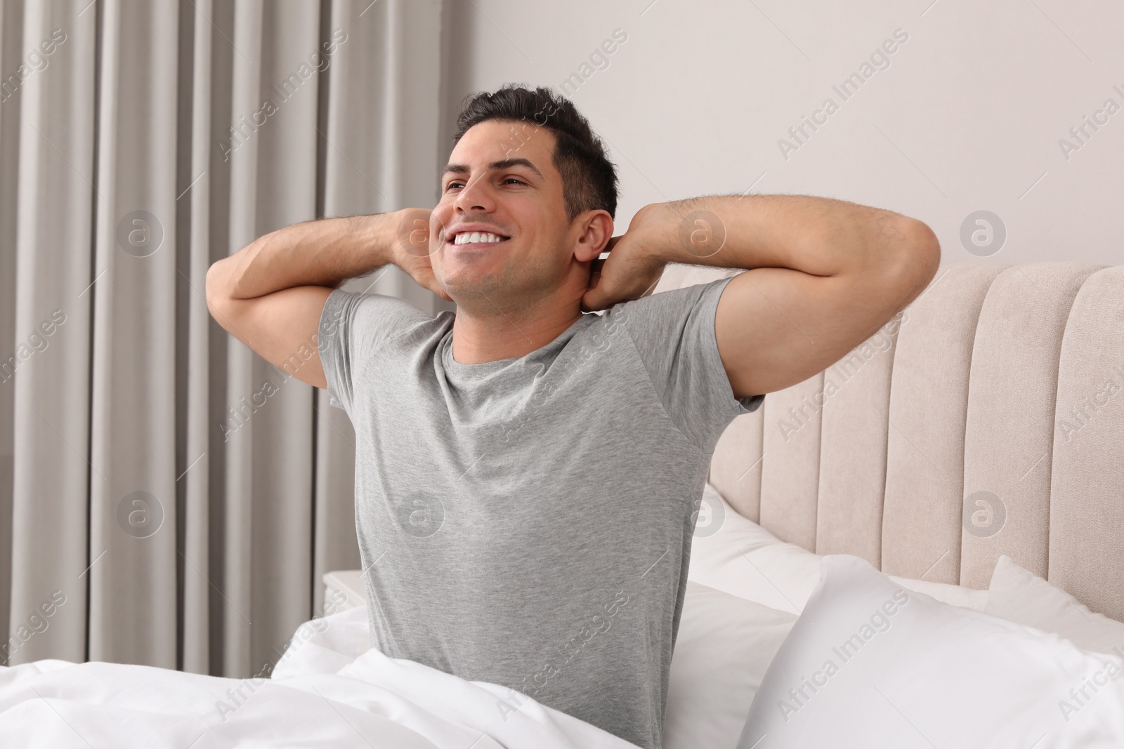 Photo of Happy man stretching in bed at home