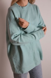 Photo of Woman in soft sweater on light background, closeup