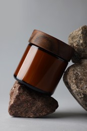 Photo of Glass jar and stones on grey background, closeup