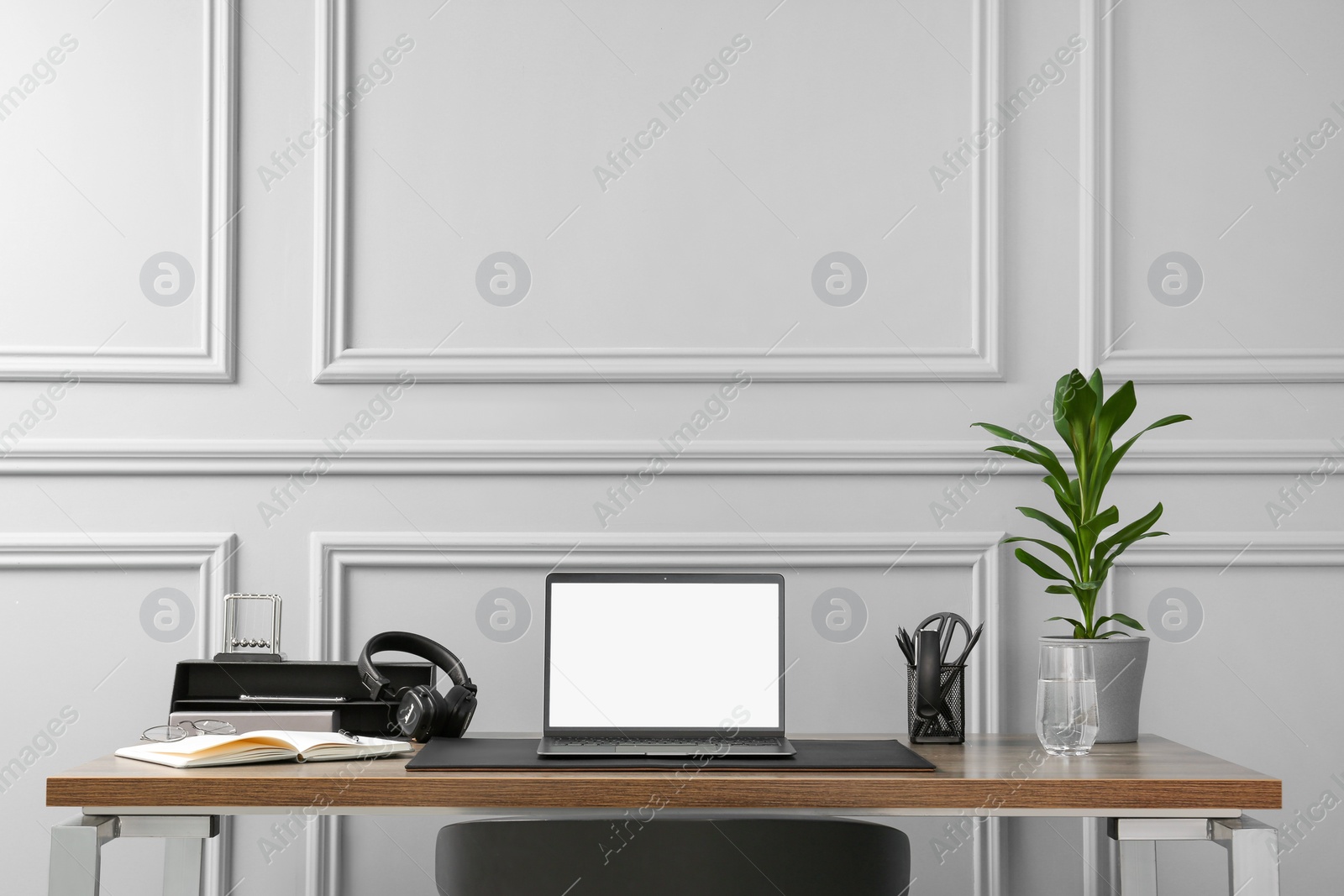 Photo of Stylish workplace with laptop, houseplant and stationery on wooden table near light grey wall