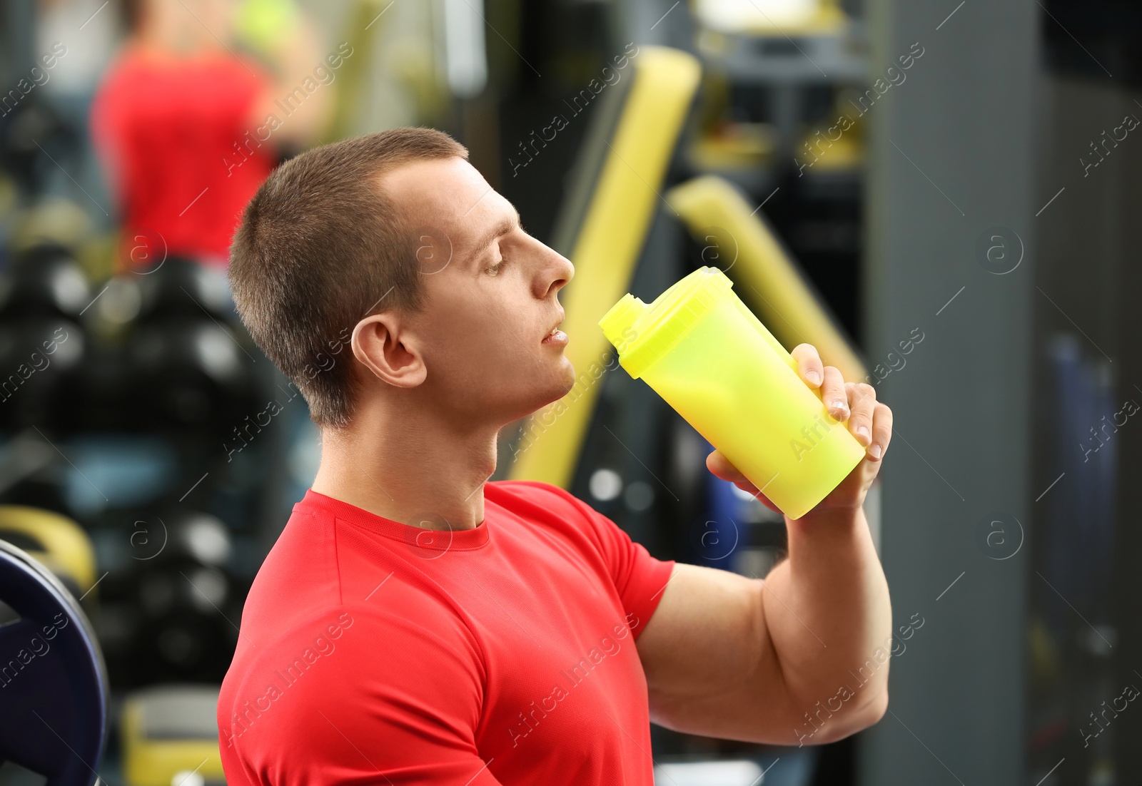 Photo of Athletic young man drinking protein shake in gym