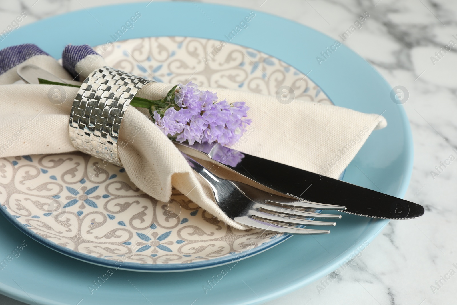 Photo of Stylish setting with cutlery and plates on white marble table, closeup