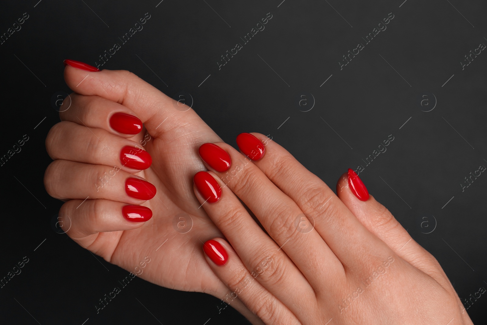 Photo of Woman with red polish on nails on black background, closeup