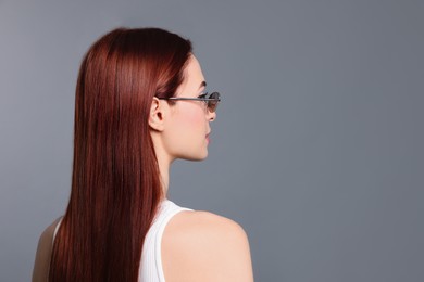 Photo of Woman with red dyed hair and sunglasses on light gray background. Space for text