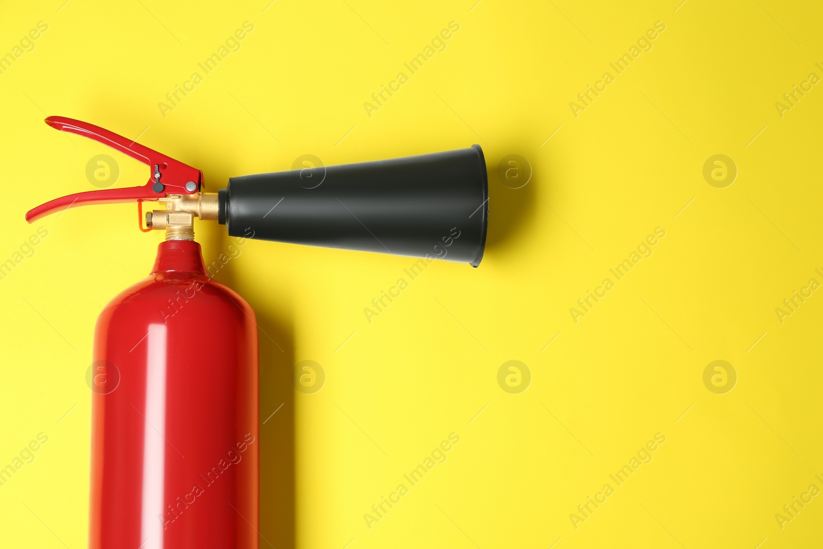 Photo of Fire extinguisher on yellow background, top view. Space for text