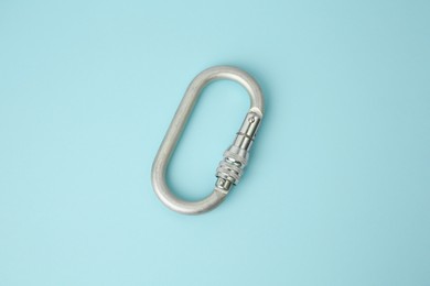 Photo of One metal carabiner on light blue background, above view