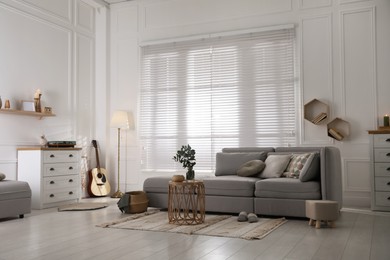 Photo of Living room with comfortable grey sofa and stylish interior elements near window