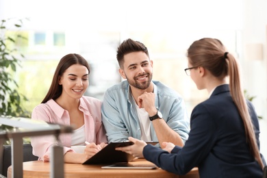 Female insurance agent working with young couple in office