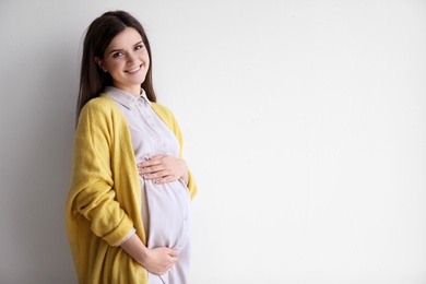 Photo of Young pregnant woman in casual clothes on light background