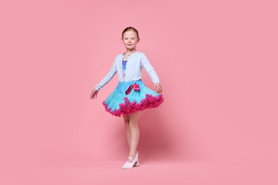 Photo of Cute little girl dancing on pink background