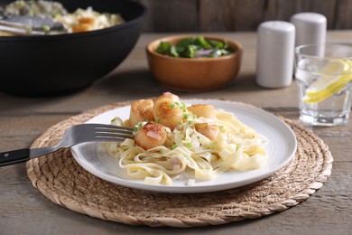Photo of Delicious scallop pasta with onion served on wooden table