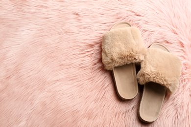 Pair of soft slippers on pink faux fur, flat lay. Space for text