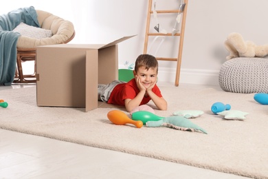 Photo of Cute little boy playing with cardboard box at home