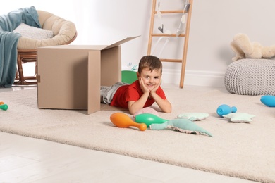 Cute little boy playing with cardboard box at home