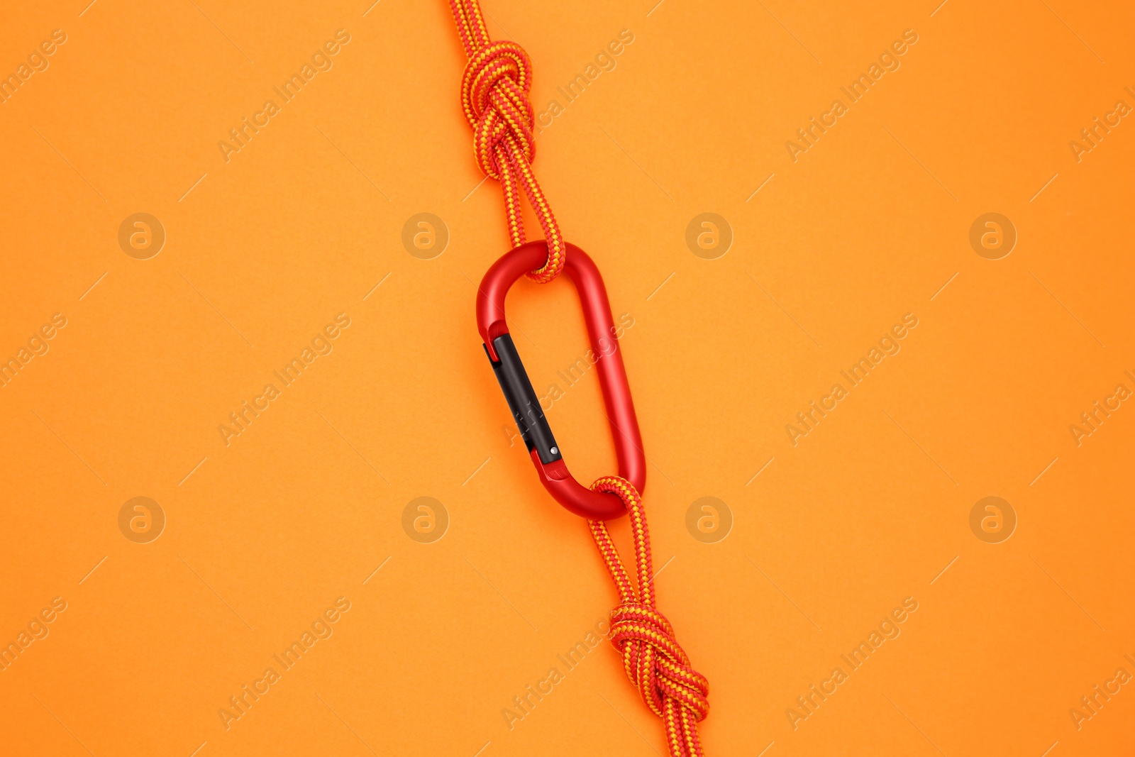 Photo of One metal carabiner with ropes on orange background, top view