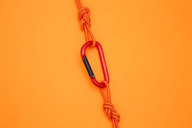 Photo of One metal carabiner with ropes on orange background, top view