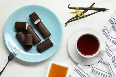 Photo of Glazed curd cheese bars, vanilla pods and tea on white marble table, flat lay