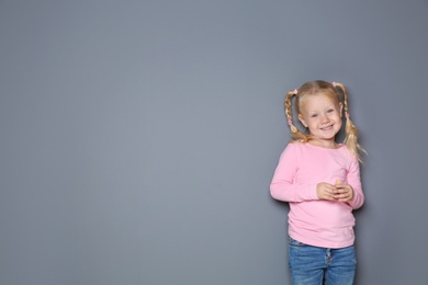 Little girl with colorful chalk standing against gray background. Space for design