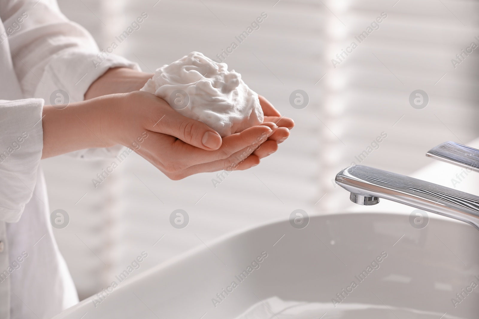 Photo of Woman washing hands with cleansing foam near sink in bathroom, closeup. Space for text