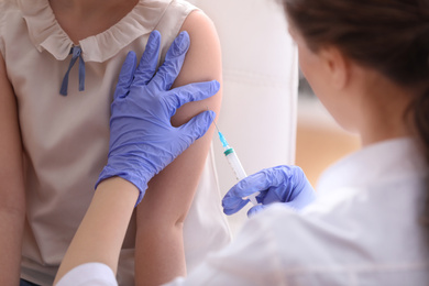 Photo of Little girl receiving chickenpox vaccination in clinic. Varicella virus prevention