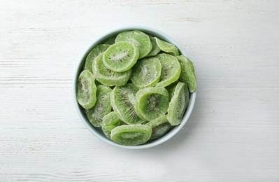 Photo of Bowl with slices of kiwi on wooden background, top view. Dried fruit as healthy food