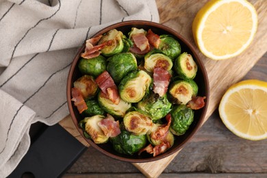 Photo of Delicious roasted Brussels sprouts, bacon and lemon on wooden table, top view