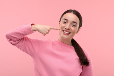 Photo of Beautiful woman showing her clean teeth and smiling on pink background