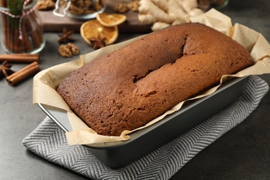 Delicious gingerbread cake in baking dish on grey table, closeup