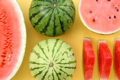Photo of Different cut and whole ripe watermelons on yellow background, flat lay