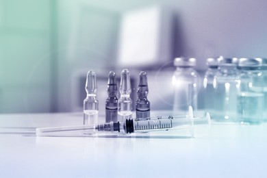 Syringe with ampules of medicines on white table