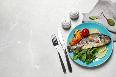 Photo of Delicious roasted fish with lemon and vegetables on grey marble table, flat lay. Space for text