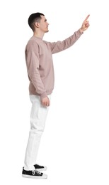 Handsome young man pointing at something on white background