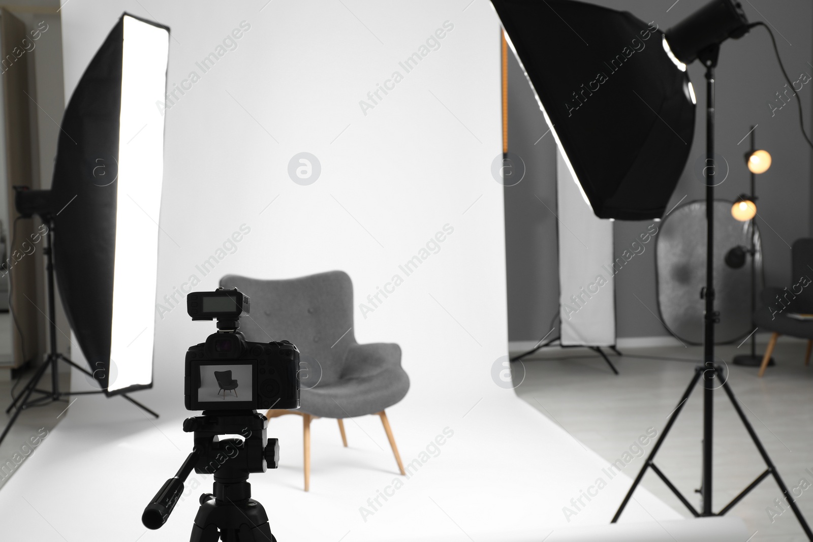 Photo of White photo background, armchair and professional lighting equipment in studio