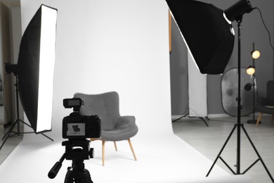 Photo of White photo background, armchair and professional lighting equipment in studio