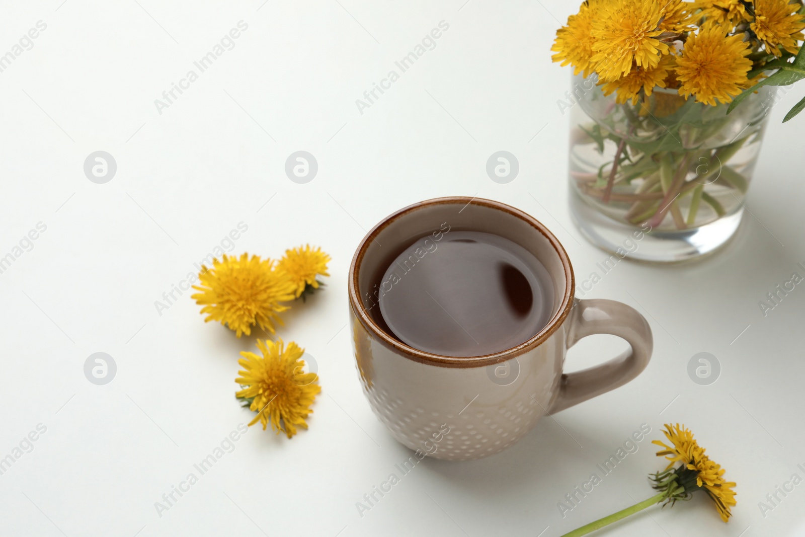 Photo of Delicious fresh tea and beautiful dandelion flowers on white background