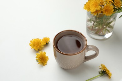 Delicious fresh tea and beautiful dandelion flowers on white background