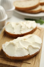 Photo of Bread with cream cheese on wooden table, closeup