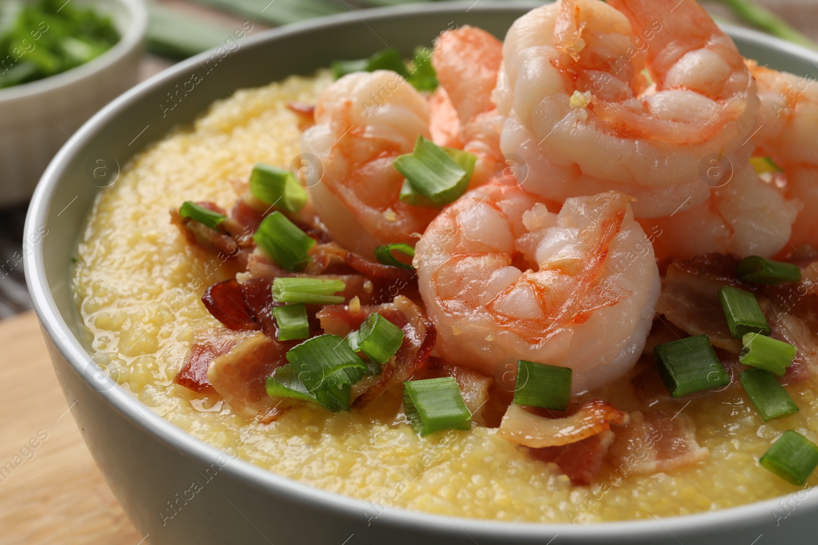 Photo of Fresh tasty shrimps, bacon, grits and green onion in bowl on table, closeup