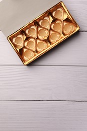 Empty box of chocolate candies on white wooden table, top view. Space for text