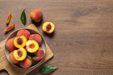Photo of Delicious juicy peaches and leaves on wooden table, flat lay. Space for text