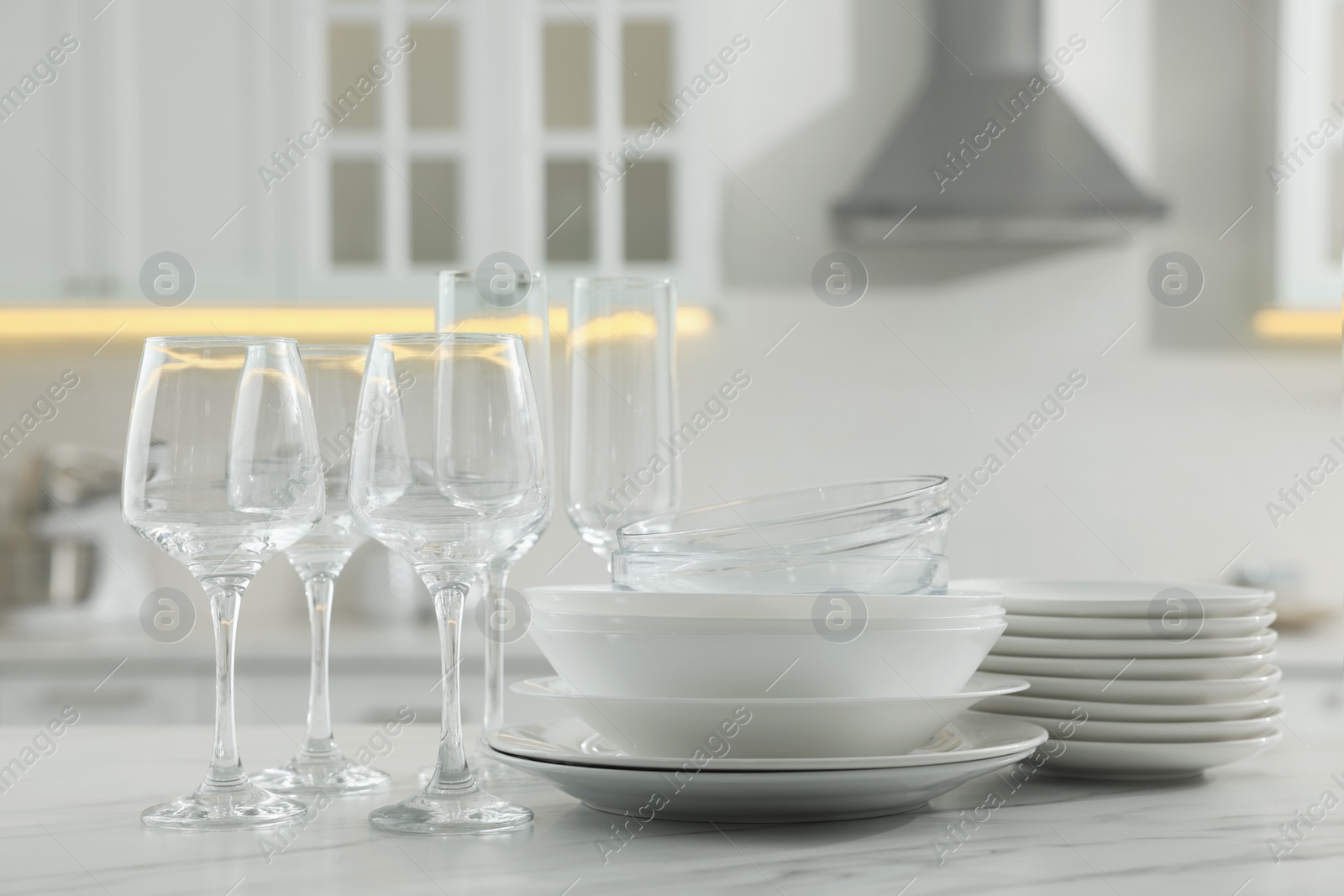 Photo of Different clean dishware and glasses on white marble table in kitchen