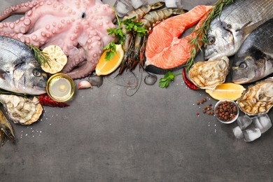 Flat lay composition with fresh raw dorado fish and different seafood on grey table. Space for text