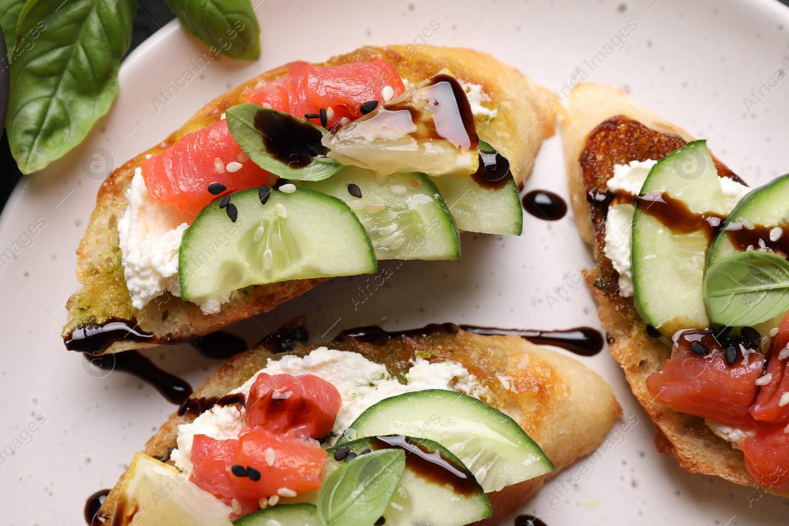 Photo of Delicious bruschettas with balsamic vinegar and toppings on plate, flat lay